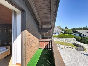 A wooden exterior wall with a window, a stone retaining wall, and a paved area with a wooden deck. - Vacation home Jung by Interhome (Gröbming)