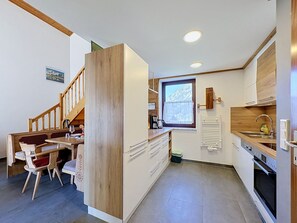 A compact kitchen with a dining area, wooden staircase, and a window with a view. - Vacation home Jung by Interhome (Gröbming)