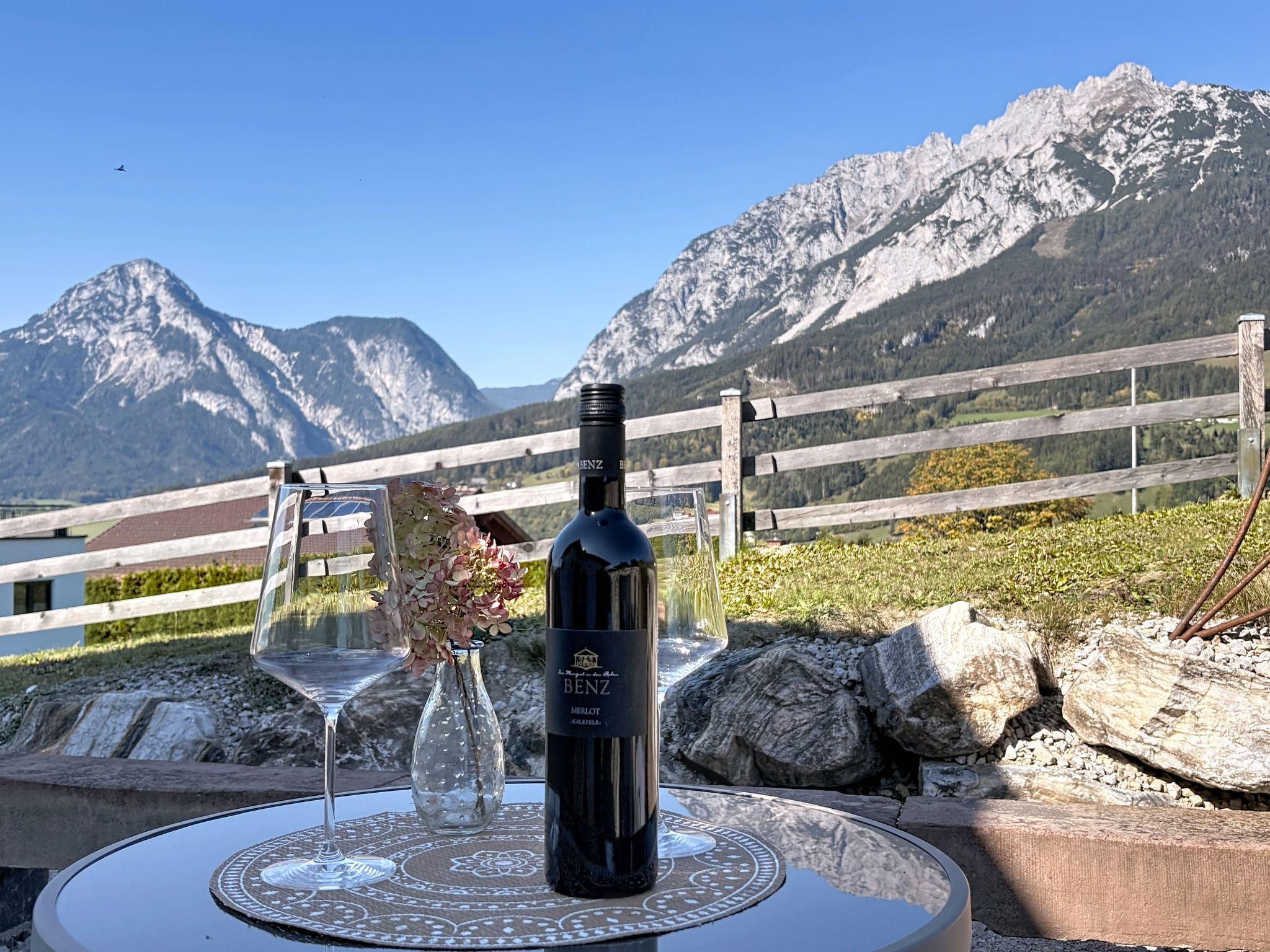 A bottle of wine on a table with a view of mountains in the background.
