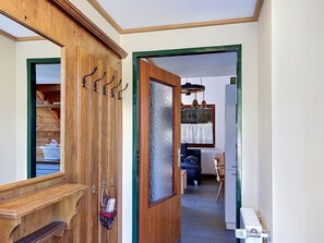 A hallway with a wooden door, a mirror, and a coat rack. - Vacation home Jung by Interhome (Gröbming)
