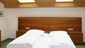 A double bed with a wooden headboard, two bedside tables, and a green carpeted floor. - Dr. Otto Schuler by Interhome (Sankt Anton am Arlberg)