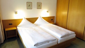 Una cama doble con sábanas blancas, dos mesitas de noche y luces fijadas a la pared.