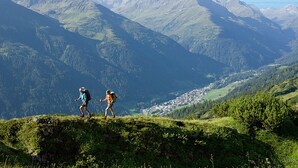 Un paisaje montañoso con excursionistas en una ladera cubierta de hierba.