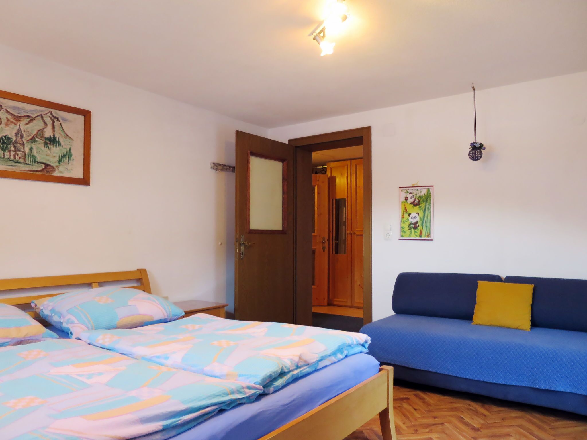 A room with a bed, a blue sofa, and a wooden door.