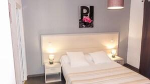 A bedroom with a large bed, two bedside tables with lamps, a wall-mounted artwork, and a hanging light fixture. - Camelia- Marjolène by Interhome (Partinello)
