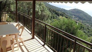 A covered outdoor area with a table and chairs, overlooking a mountainous landscape. - Camelia- Marjolène by Interhome (Partinello)