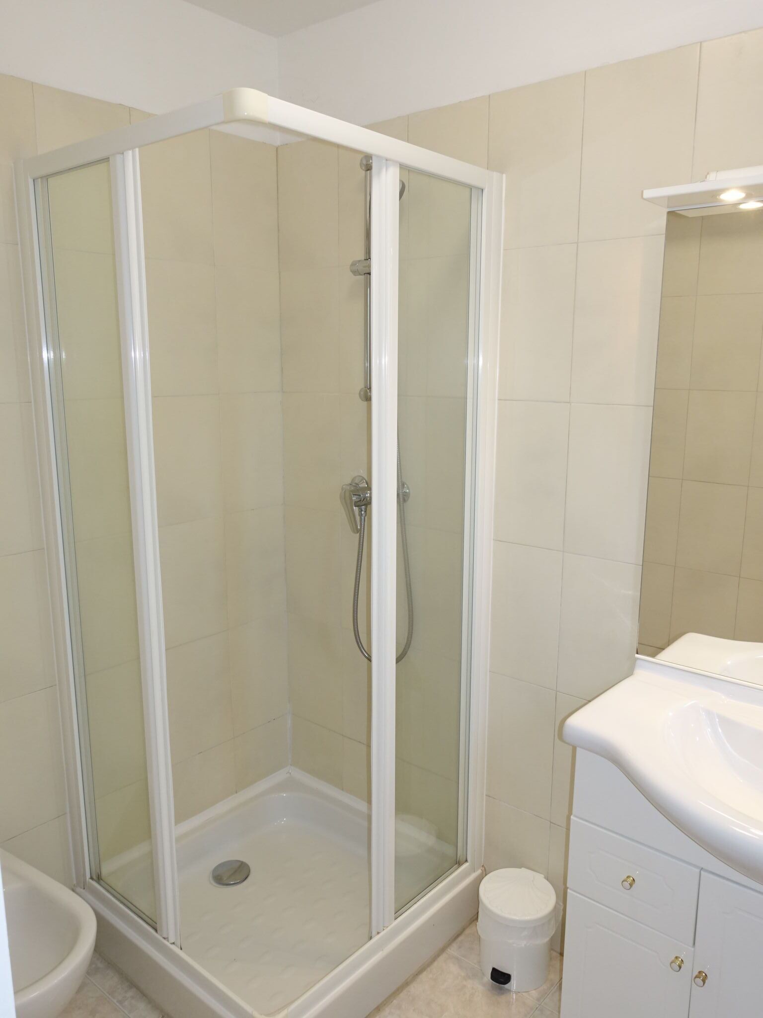 Une salle de bain avec une douche à parois de verre, un lavabo blanc et des toilettes.