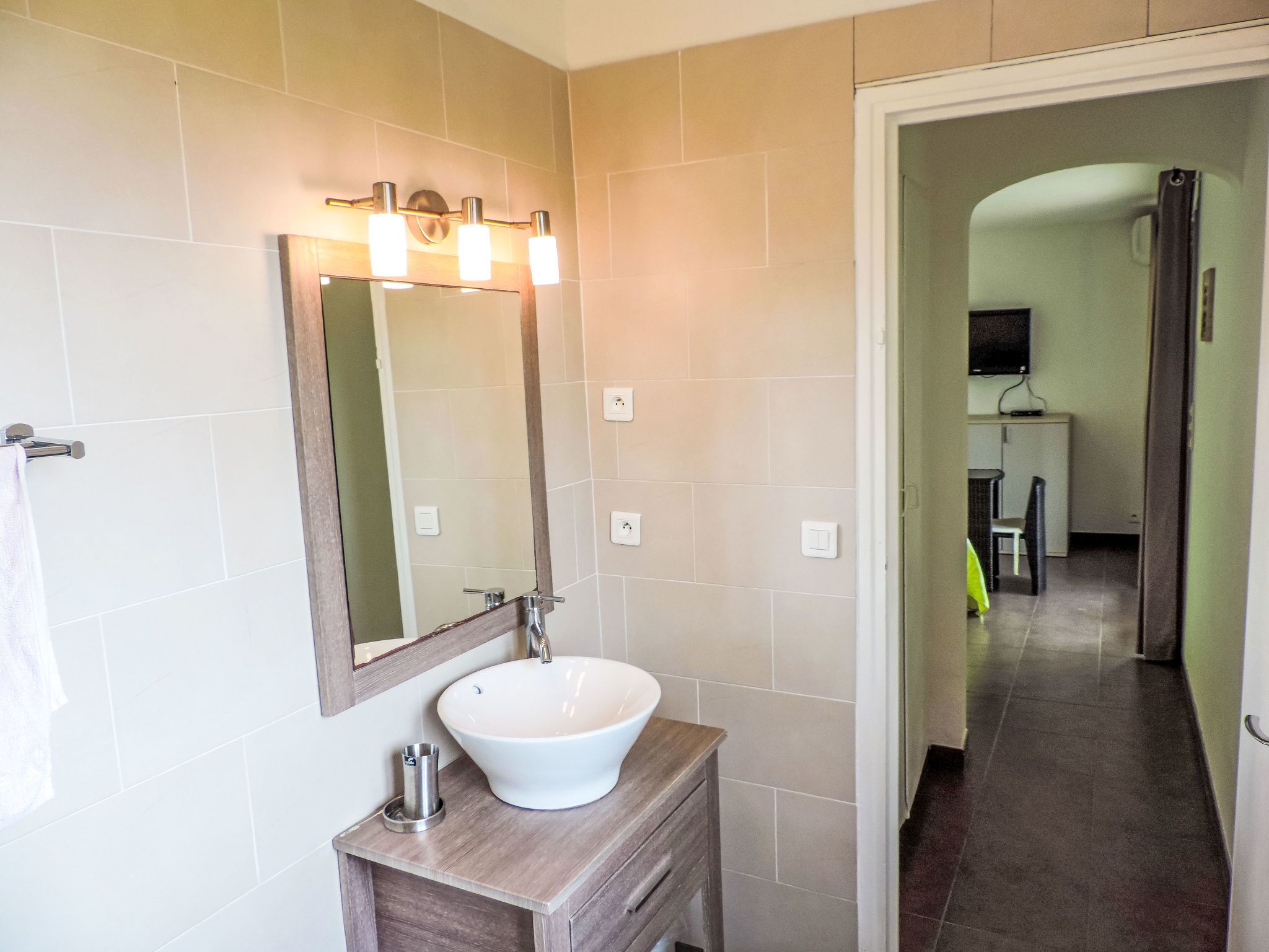 A bathroom with a white sink, a mirror, and a lighted vanity.