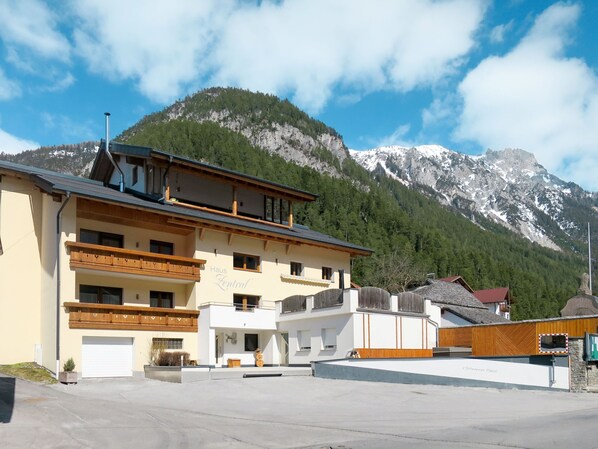 A building with a balcony, a garage, and a mountain backdrop. - Zentral by Interhome (Pettneu am Arlberg)