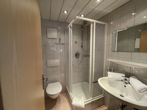 A modern bathroom with a glass-enclosed shower, a toilet, and a sink with a mirror. - Zentral by Interhome (Pettneu am Arlberg)