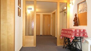 Un pasillo con puertas de madera, una mesa con mantel rojo y una máquina de coser.