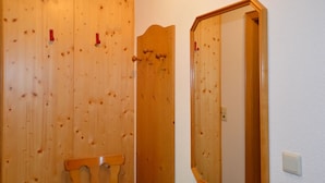 Een houten deur met een spiegel en een stoel in een kamer met houten lambrisering.