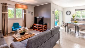 A modern living room with a grey sofa, a wooden coffee table with decorative items, a blue armchair, and a television. - Villa Marie-Jo by Interhome (Prunete)