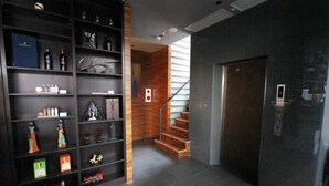 A modern hotel lobby with a staircase, a black elevator, and a variety of decorative items on shelves. - Wolken Lodge (Pingtung)