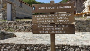 Un letrero de madera con texto en italiano, que indica direcciones y distancias a varios lugares como Parcorsu Poghju, Etape Poghju, Stage Poghju, Vecchia Mina y Ghisoni.