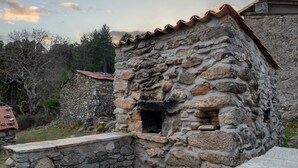 Un edificio de piedra con techo de tejas, una pequeña ventana y una escalera de piedra que lleva a la entrada.