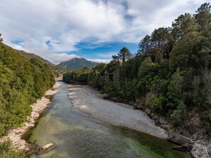 A river flowing through a forested valley with mountains in the background.