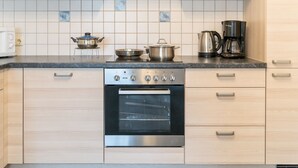 A kitchen with light wood cabinets, a stainless steel stove, a built-in oven, and a coffee maker on the countertop. - Al Vietta by Interhome (Kappl)