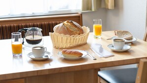A breakfast setting with bread, juice, coffee, and pastries on a wooden table. - Al Vietta by Interhome (Kappl)