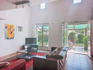 Un soggiorno con televisore, divano, tavolino e opere d'arte appese al muro.