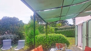 An outdoor dining area with a table set for four, surrounded by orange chairs, under a green canopy. - Olivier by Interhome (Mougins)