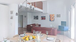 A dining area with a table set for four, a chandelier, and a sofa in the background. - Olivier by Interhome (Mougins)