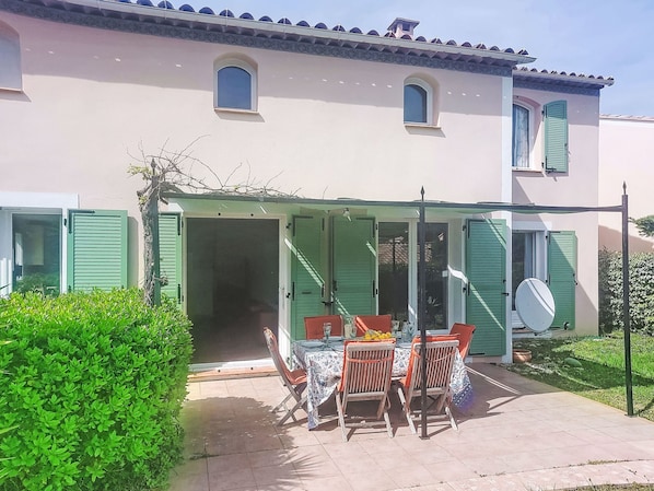 A house with a covered patio, a table with chairs, and a satellite dish.