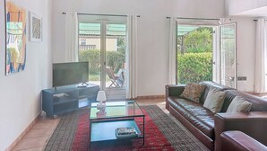 A living room with a sofa, coffee table, TV, and artwork on the wall. - Olivier by Interhome (Mougins)