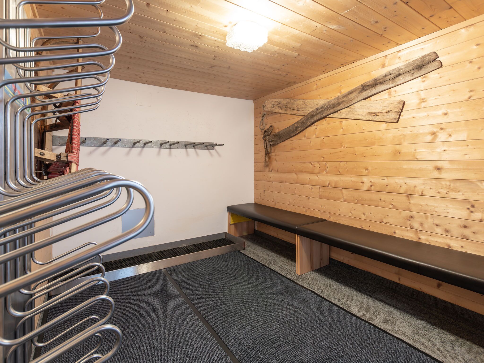 A sauna with a metal bench, a wooden wall, and a metal rack.