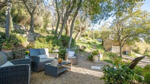 An outdoor seating area with wicker furniture, a small table, and potted plants. - Le Clermont by Interhome (Chateauneuf de Grasse)