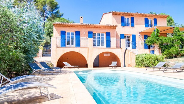 Uma vila em estilo mediterrâneo com piscina, área de estar ao ar livre e varanda coberta.