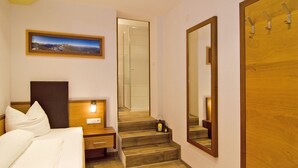 Une chambre d’hôtel comprenant un lit, une table de chevet, un bureau, un miroir, un escalier et une porte.