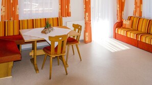 Ruokailutila, jossa on pöytä ja tuolit, sohva sekä geometrisella kuviolla varustetut verhot.