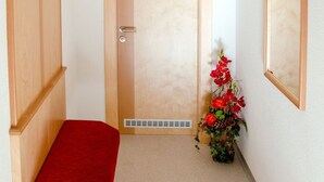 A narrow hallway with a wooden bench, a door, and a small flower arrangement. - Apartment Jäger by Interhome (Kappl)