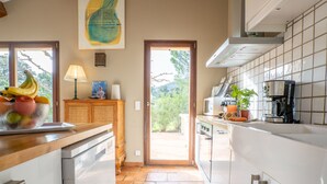 Eine Küche mit Blick ins Freie, einer Obstschale, einer Mikrowelle und einer Kaffeemaschine.