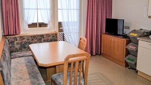 Une pièce de taille modeste comprenant un canapé, une table à manger, un téléviseur et des bacs de rangement.