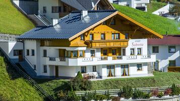 Ein mehrstöckiges Hotel mit einer markanten gelben Fassade, einem Schild mit der Aufschrift "APART Subretta" und einer Steinsichtmauer im Vordergrund.