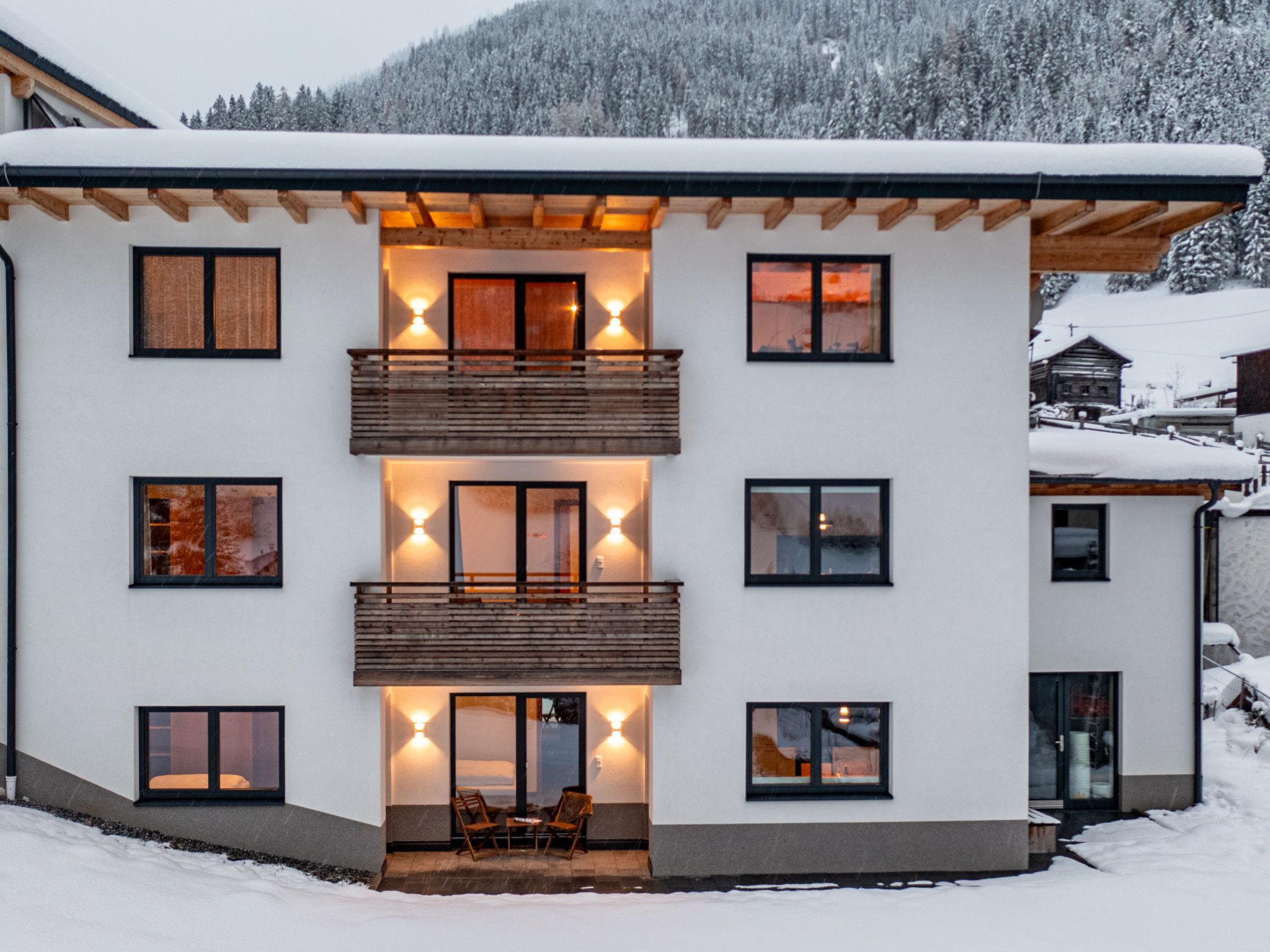 Un immeuble moderne à plusieurs étages, doté de balcons, de grandes fenêtres et surplombant un paysage enneigé.
