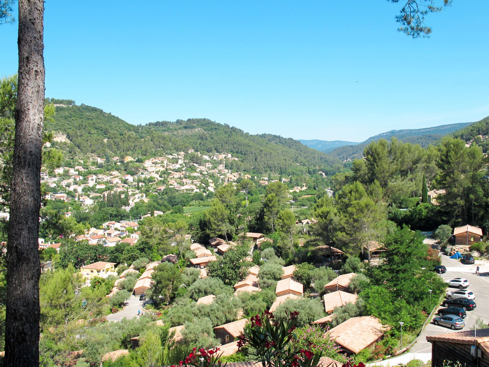 A hillside village with traditional houses, a parking area, and a clear view of the surrounding landscape.