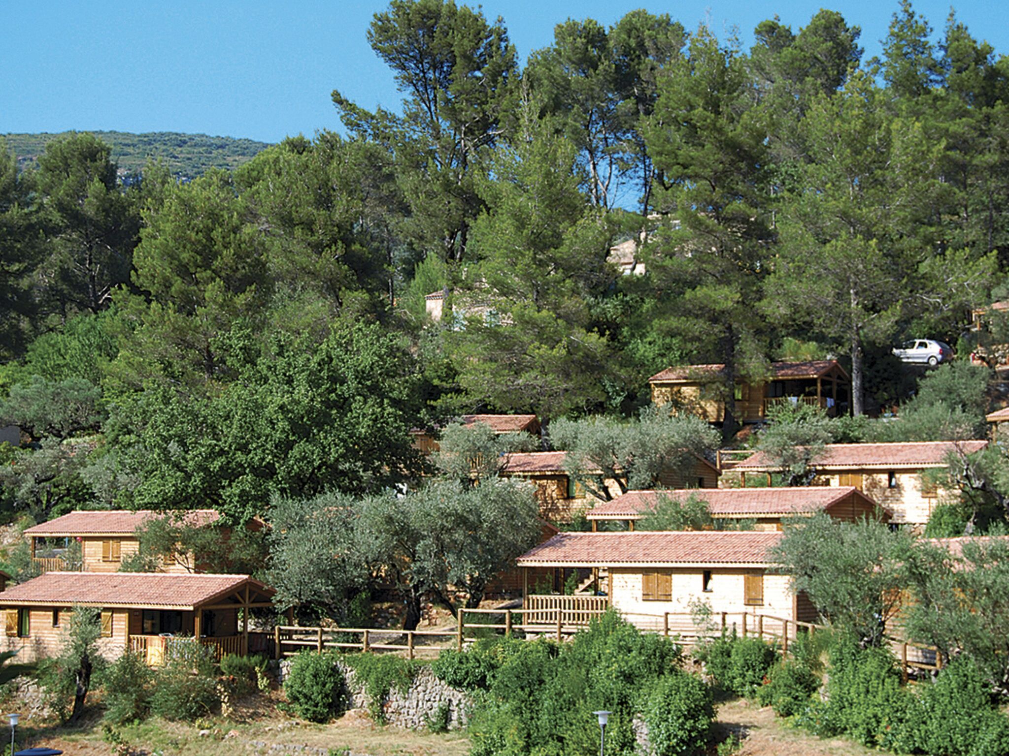 A cluster of rustic cabins with terracotta roofs, surrounded by dense greenery and trees.