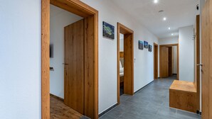 A hallway with wooden doors, a bench, and a tiled floor.