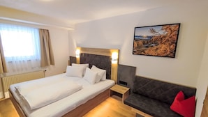 A hotel room with a large bed, a bedside table, a sofa, and a painting on the wall. - Apart Garni Wachter by Interhome (Kappl)