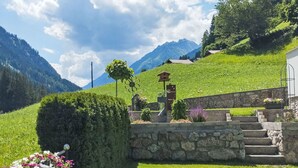 A stone staircase leading up to a wooden structure with a flower bed and a birdhouse. - Apart Garni Wachter by Interhome (Kappl)