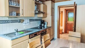 A kitchen with wooden cabinets, a countertop, and a dining table. - Apart Garni Wachter by Interhome (Kappl)