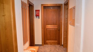 Ein schmaler Flur mit Holztüren, Teppichboden und einer kleinen Holzkiste mit einer Spitzendecke.