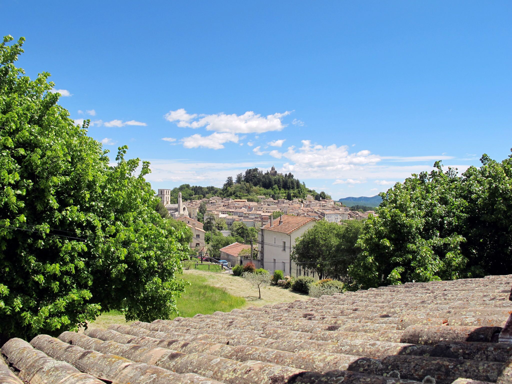 A historic town with terracotta-roofed buildings, a prominent church, and lush greenery.