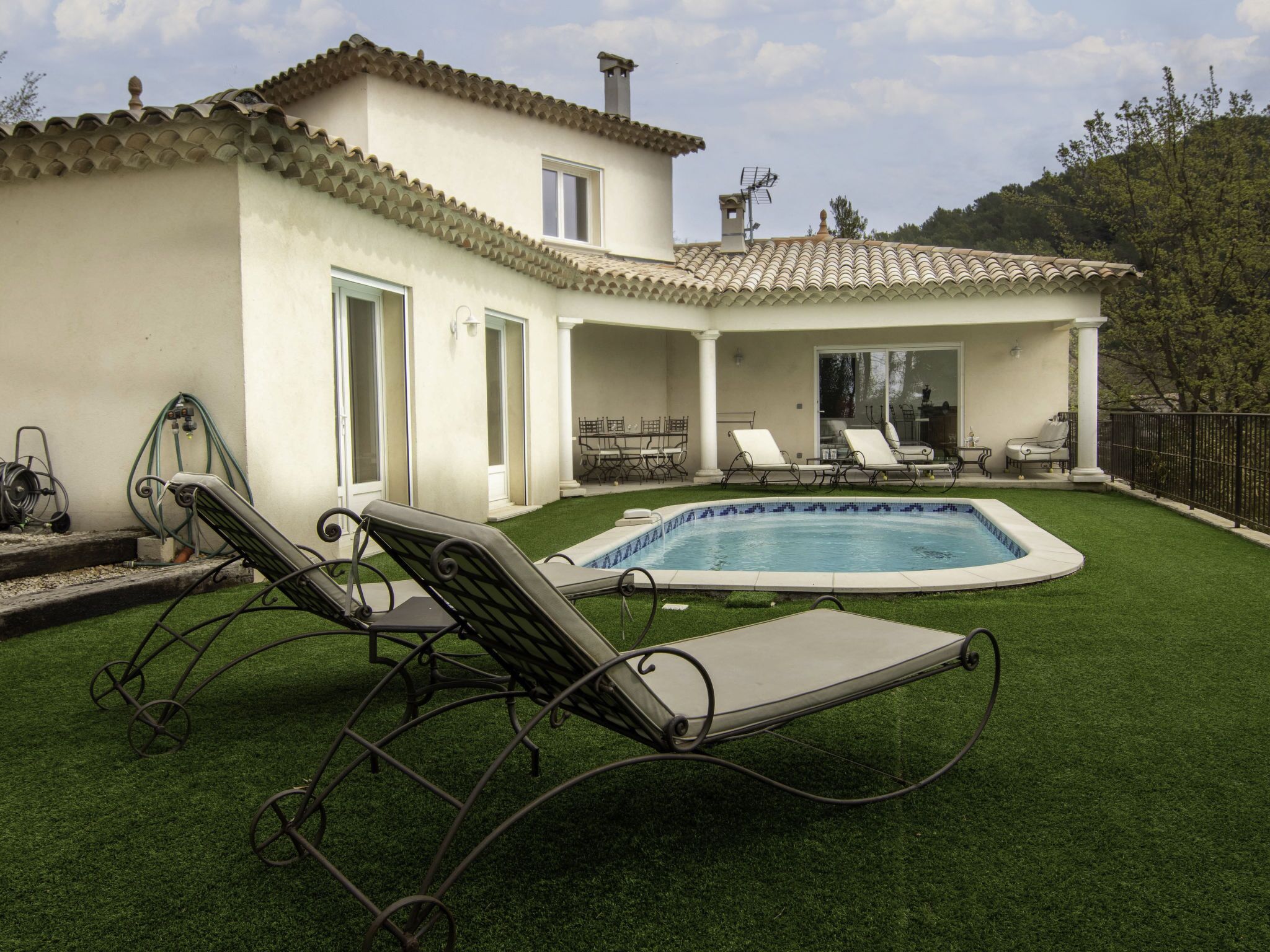 Ein Poolbereich mit Pool, Liegestühlen und einer Terrasse mit Gartenmöbeln.