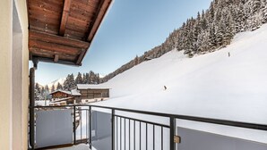 Ein Balkon mit Blick auf einen verschneiten Berg und ein Holzhaus.