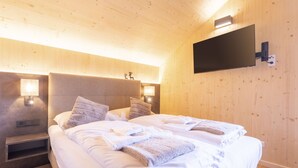 A modern bedroom with a large bed, two bedside tables with lamps, and a mounted TV on the wall. - #7b mit Sauna & Pool by Interhome (Sankt Georgen am Kreischberg)