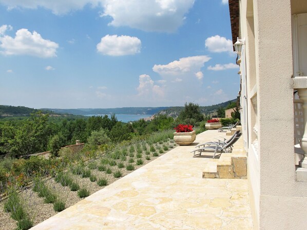 A stone pathway leading to outdoor seating with a view of a coastal landscape.
